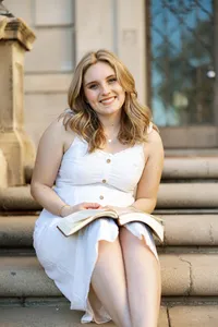 High school senior girl sitting on stone steps with a book in her lap, natural outdoor senior portrait by Kaitlyn Dawn Photography.