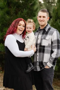Mother and father smiling while holding their baby outdoors, candid natural light family portrait by Kaitlyn Dawn Photography, professional family photographer.