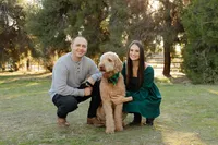 Couple crouching beside their dog smiling during an outdoor lifestyle portrait session photographed by Kaitlyn Dawn Photography.