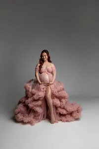 Elegant maternity portrait of a pregnant woman in a blush pink couture maternity gown holding her baby bump during a studio session by Kaitlyn Dawn Photography.