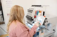 Two women reviewing colorful thread samples in an embroidery workspace. Photograph by Yucaipa branding photographer Kaitlyn Dawn Photography.