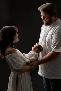 Mother and father gently holding their sleeping newborn baby girl during an emotional studio newborn family photography session by Kaitlyn Dawn Photography.
