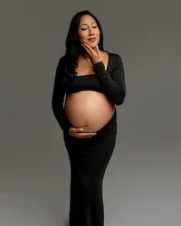 Pregnant woman in a black studio maternity dress gently holding her baby bump during a maternity portrait session by Kaitlyn Dawn Photography.