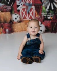 Denim overalls, the sweetest grin, and a farm setup full of charm. Captured by Yucaipa cake smash photographer Kaitlyn Dawn Photography.
