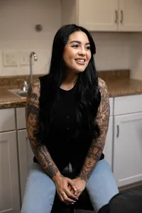 Woman with long dark hair and tattoos standing in a modern salon setting. Photograph by Yucaipa branding photographer Kaitlyn Dawn Photography.