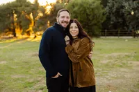 Couple embracing closely in a grassy park at sunset, warm golden hour portrait captured by Kaitlyn Dawn Photography, professional couples’ photographer.