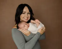 Mother holding her sleeping newborn baby during a studio newborn portrait session with newborn photographer Kaitlyn Dawn Photography.