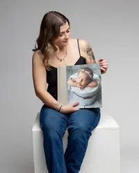 Photographer holding a custom newborn album featuring a sleeping baby portrait, Kaitlyn Dawn Photography, Yucaipa newborn photographer.
