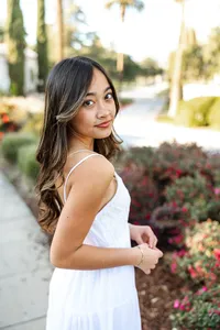 High school senior girl posing on a garden path with flowers and greenery, senior photography session by Kaitlyn Dawn Photography.