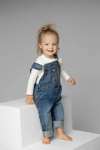 Toddler girl standing on modern white studio steps in a neutral gray setting, natural light child portrait captured by Kaitlyn Dawn Photography, children’s photographer.