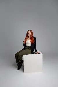 Professional branding portrait of red-haired woman seated on white cube, smiling. Photograph by Yucaipa branding photographer Kaitlyn Dawn Photography