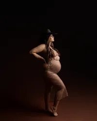 Pregnant woman wearing a sheer rhinestone maternity gown and cowboy hat during a dramatic studio maternity photography session by Kaitlyn Dawn Photography.