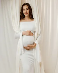 Pregnant woman smiling in a white dress surrounded by flowing fabric, celebrating pregnancy in an Yucaipa maternity session with Kaitlyn Dawn Photography.