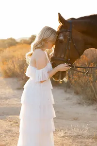 High school senior girl standing beside a horse during golden hour in a field, natural light senior portrait by Kaitlyn Dawn Photography.