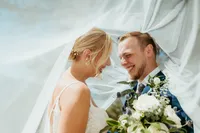 Bride and groom smiling under flowing veil during intimate wedding day portrait in Colorado.