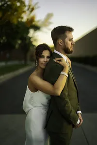 Bride embracing groom during golden hour wedding portraits in cityscape background.