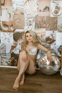 Blonde woman in white lingerie sits on a wooden floor beside a mirrored disco ball, surrounded by a dreamy collage of fashion and beauty images.