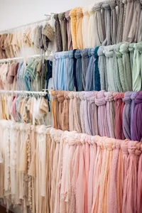 Rows of newborn wraps and textured fabrics arranged in cream, pink, lavender, and other soft colors.
