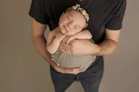 close up of father holding sleeping newborn baby wearing floral headband
