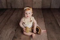 baby in cream lace outfit with wooden texture background during fine art studio milestone session in Los Angeles