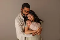 mom and dad cradling newborn baby during luxury studio newborn photoshoot in Los Angeles
