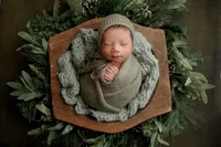 newborn Gio posed in wooden bowl with green foliage during luxury studio portrait in North Hollywood
