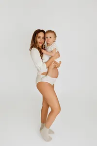 mother-to-be in neutral tones posing with her young child during timeless studio maternity session