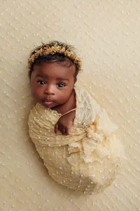 Los Angeles newborn portrait baby Aubrey wrapped in yellow knit wrap with eyes open during fine art newborn portrait session in Los Angeles,