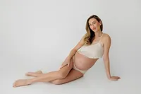 expecting mother seated during elegant studio maternity photoshoot