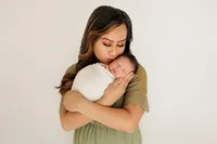 mother cradling newborn baby during studio photography photoshoot in Los Angeles