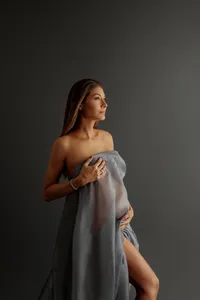 portrait of pregnant woman wrapped in flowing fabric during fine art maternity portrait session in North Hollywood, dark moody setting