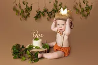 baby in neutral tones with cake highlighting first birthday and foliage props during elegant milestone photography session in North Hollywood