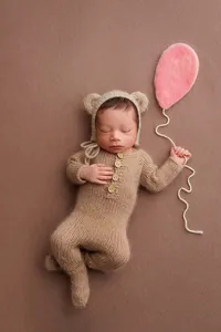 sleeping newborn posed with ballon on brown backdrop