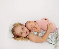 newborn baby laying on older sister's chest