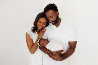 mom and dad cradling newborn baby, dressed in white