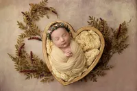 baby Parker in heart-shaped wooden bowl with dried flowers during newborn portrait session