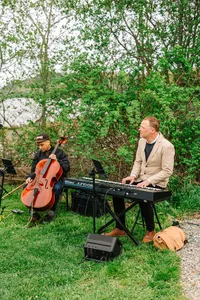 Cellist and pianist playing for the ceremony beneath the trees