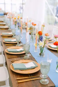 Long reception table with blue runners, gold chargers and taper candles