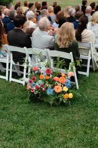 Guests watching the ceremony beside a floral aisle arrangement