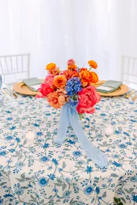 Low centerpiece of coral blooms with blue ribbon on a round table