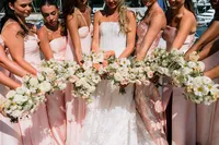 Bridesmaids in blush holding garden bouquets around the bride