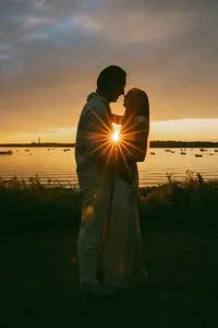 Couple silhouetted against a golden sunset over Casco Bay
