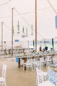 Tented reception set with long tables and hanging greenery