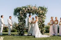 Waterfront ceremony beneath a lush floral arch at the Samoset Resort in Rockport, Maine