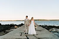 Patty and Cooper walking along a stone jetty by the water in Rockport, Maine