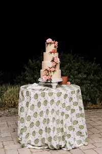 Tiered wedding cake with florals on a patterned table in the evening