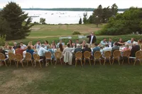 Guests seated at long tables on the island lawn