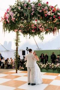 First dance on a checkered dance floor under hanging florals in the tent