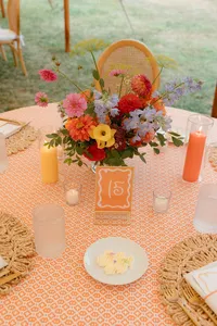 Colorful centerpiece on a reception table set with rattan chairs
