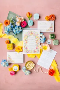 Invitation suite styled with blue and coral flowers on pink